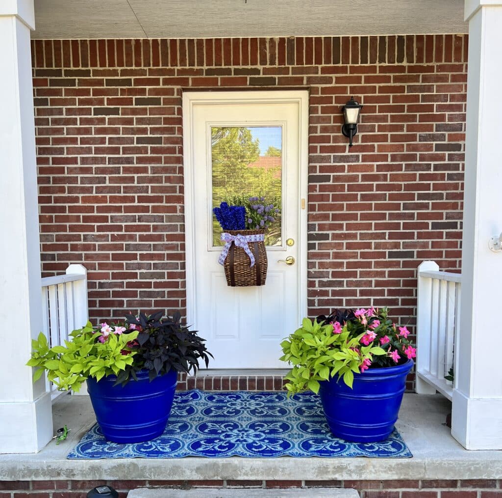 A small covered side porch with two large planters of plants that are good in full sun with a west exposure.