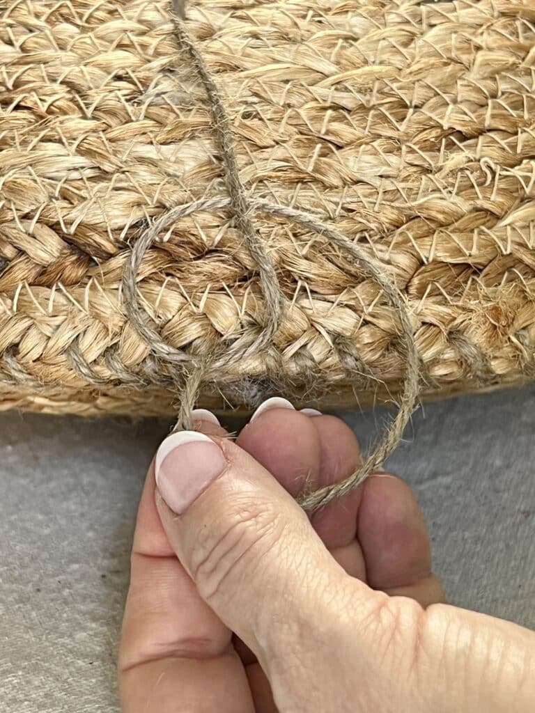 Tying a knot once the two placemats have been sewn together to create the DIY boho pillow.