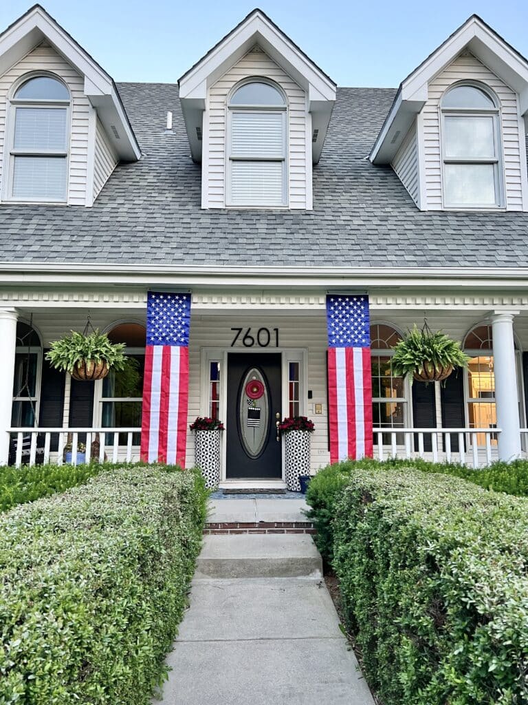 Two banner flags hanging from the front porch for July 4th.