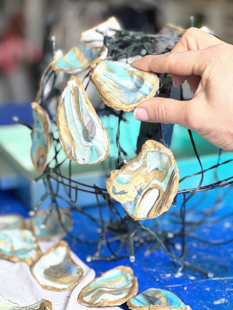 Attaching oyster shells to the globe to create a DIY chandelier.
