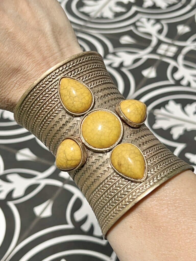How to Wear a Cuff Bracelet with Style: A gold cuff bracelet filled with yellow stones.