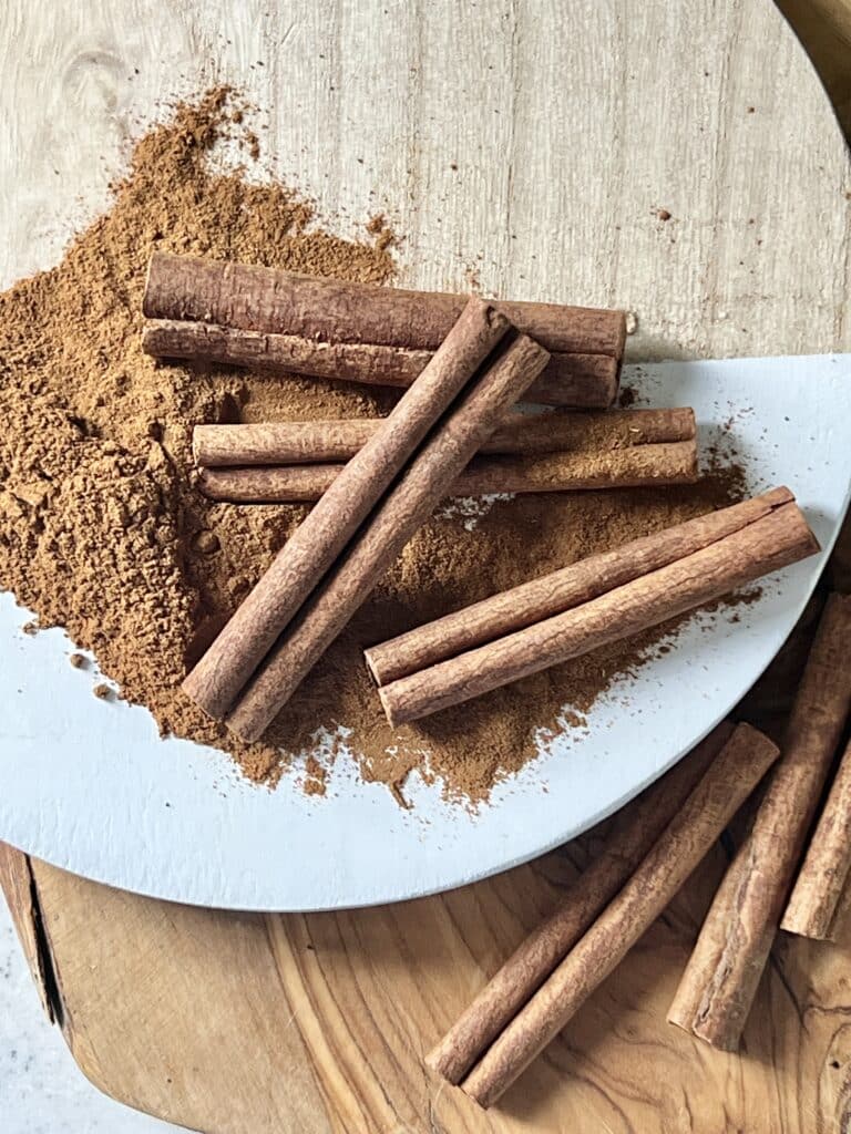 Benefits of lip scrub: Cinnamon sticks sitting on top of a mound of freshly ground cinnamon.