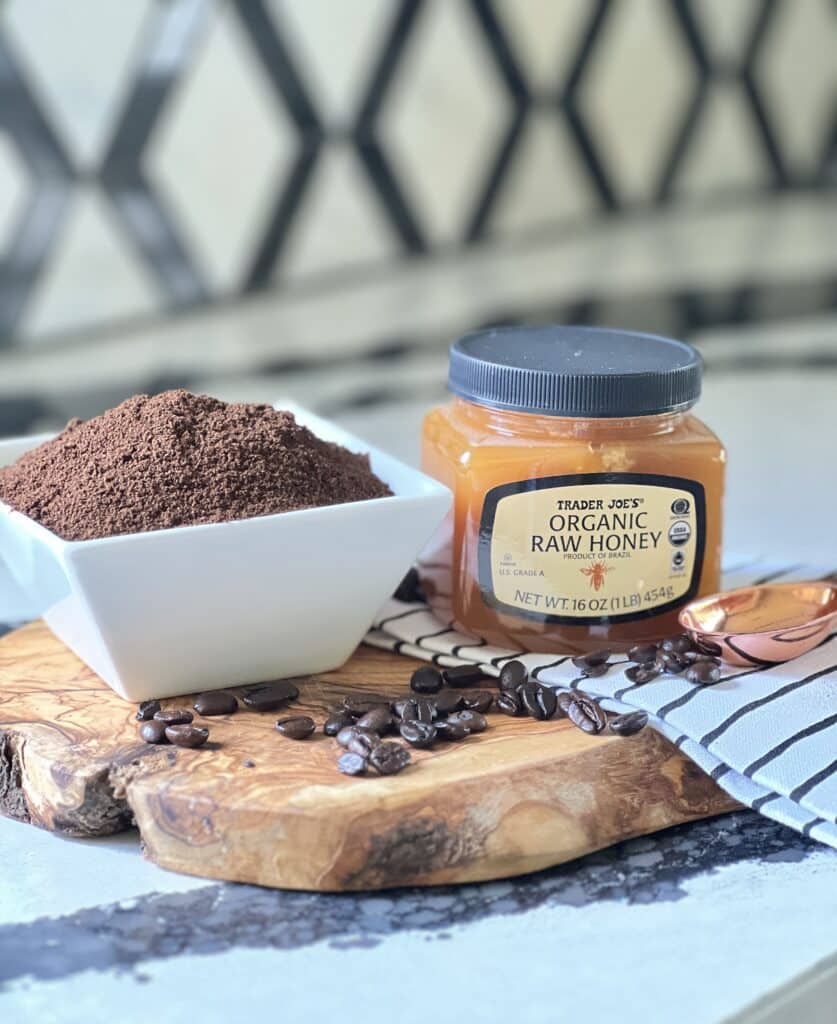 A bowl of ground coffee and a jar of organic raw honey being used in a beneficial lip scrub.