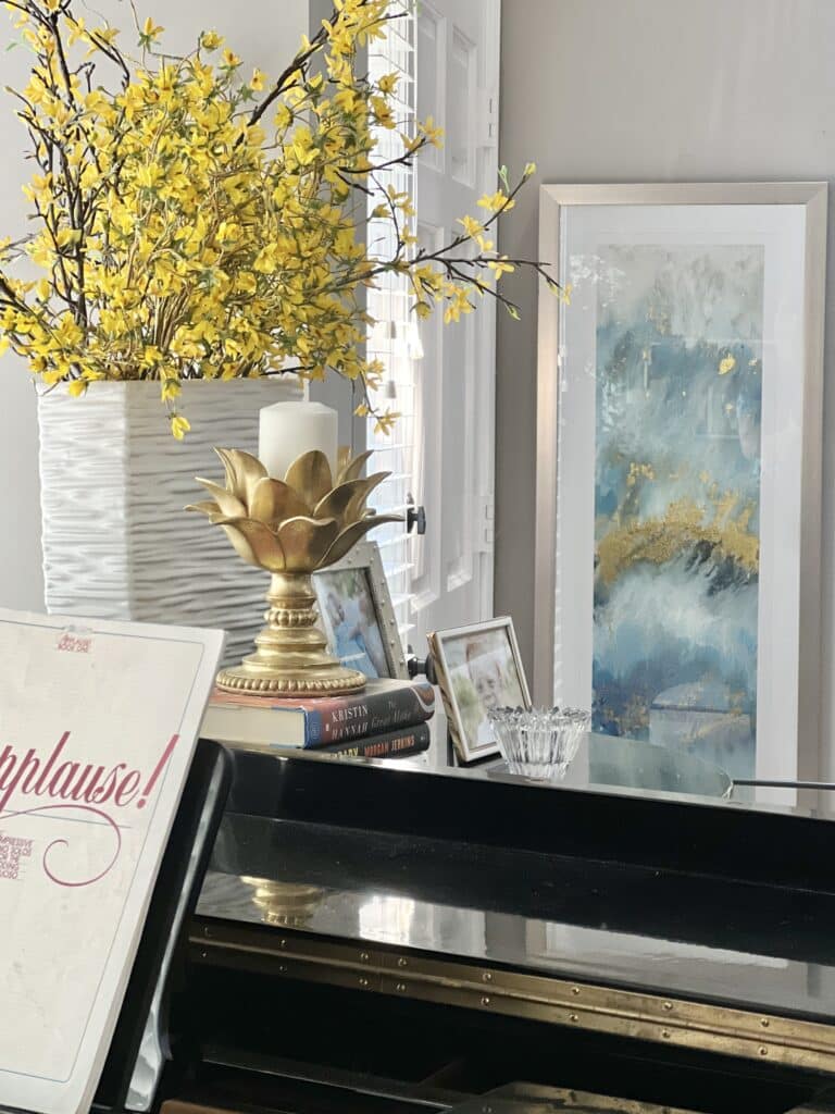 piano decorating ideas: wall art, faux flowers, and a candle decorating the piano area.