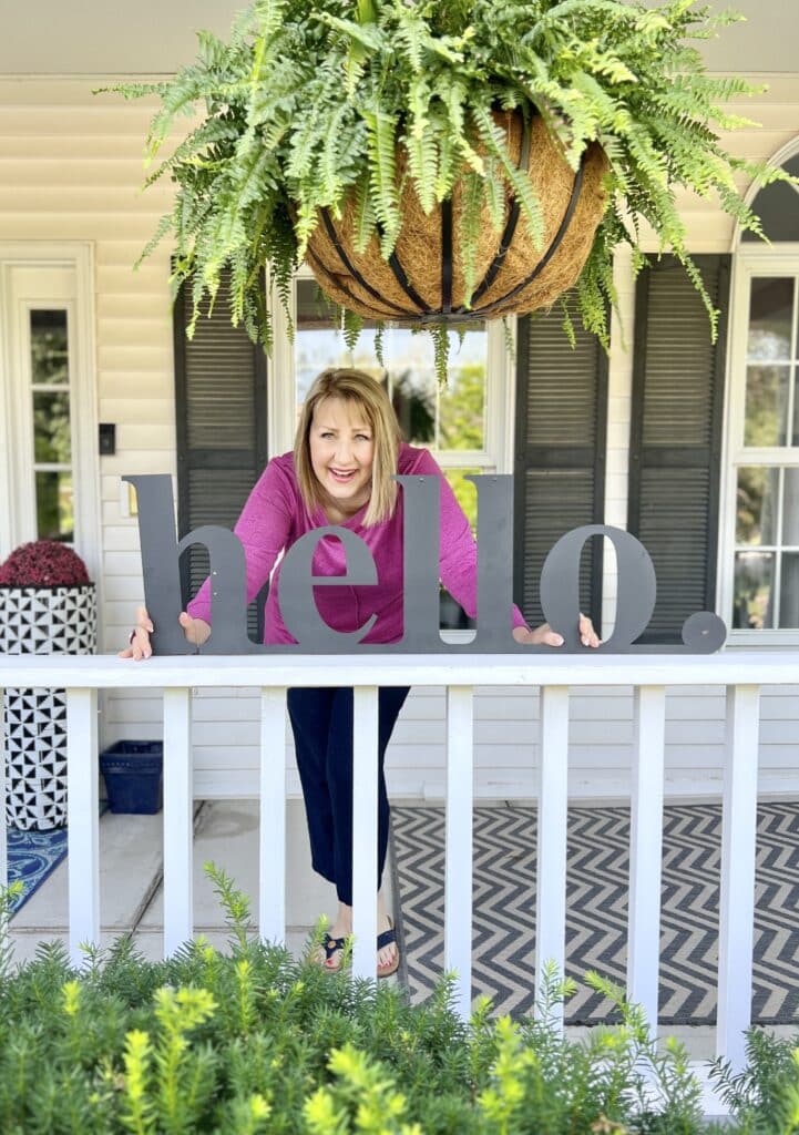 35 Thoughtful New Neighbor Housewarming Gift Ideas: Missy holding a metal sign that says "hello"