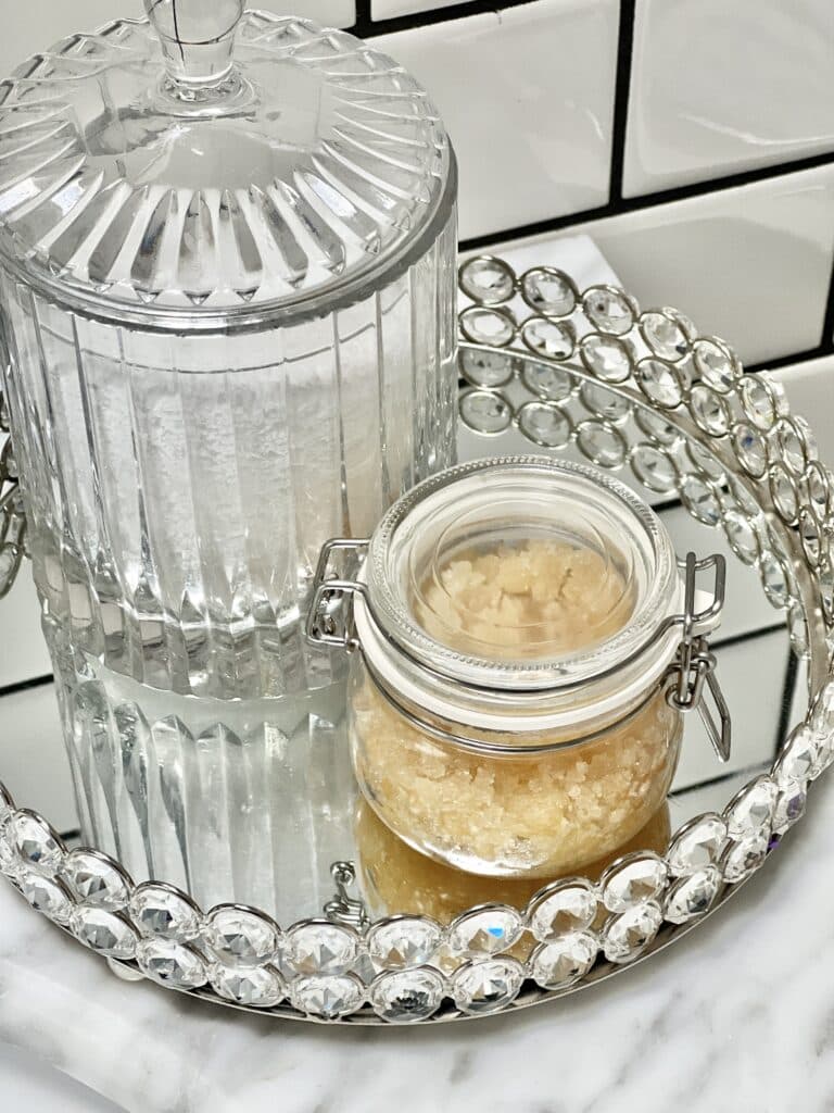 Benefits of lip scrub: A glass jar of a DIY lip scrub sitting on a bathroom vanity.