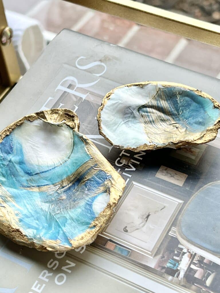 Two decoupaged oyster shells sitting on a stack of books.