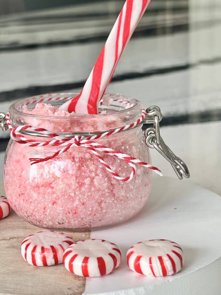 Benefits of lip scrub: a peppermint lip scrub with a candy cane sticking out of the top.