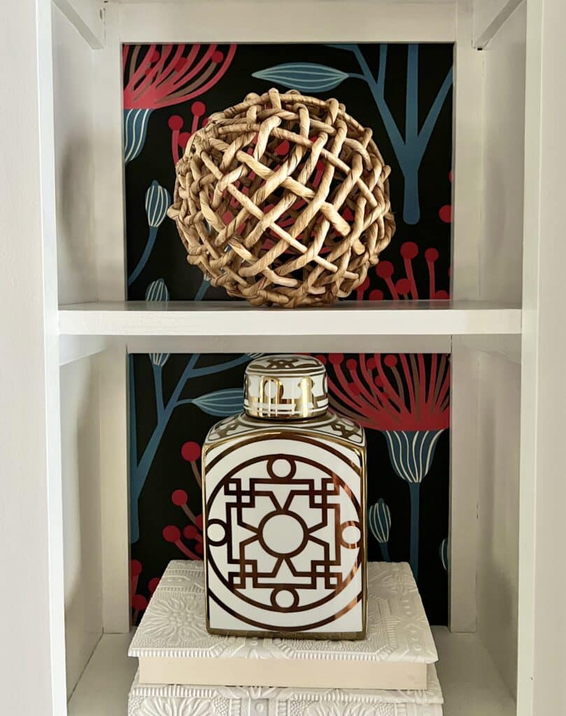 A rattan orb sitting on a bookshelf for summer.