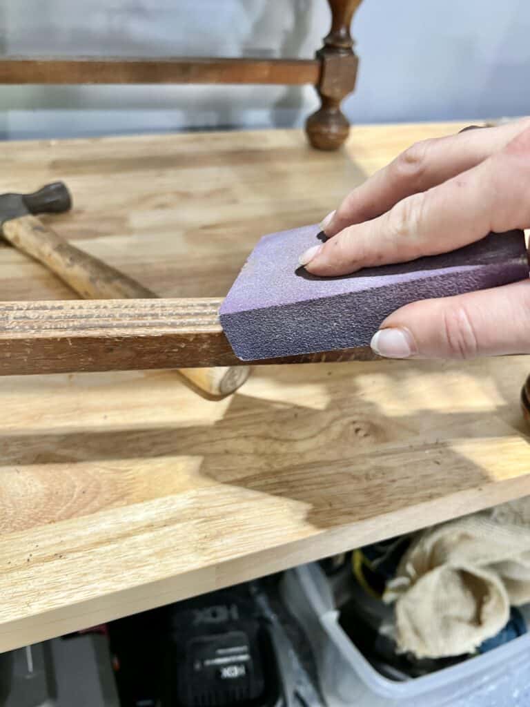 Sanding the frame of a wood chair.