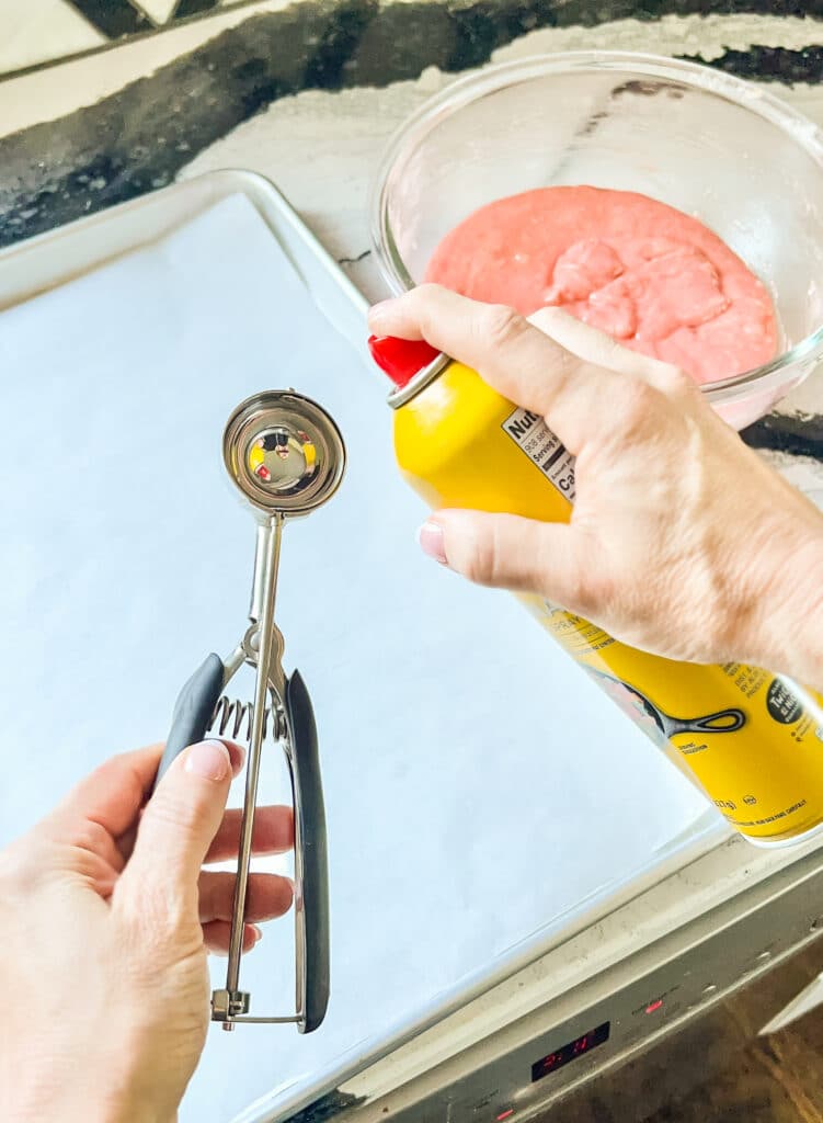 Spraying an ice cream scoop with cooking spray.