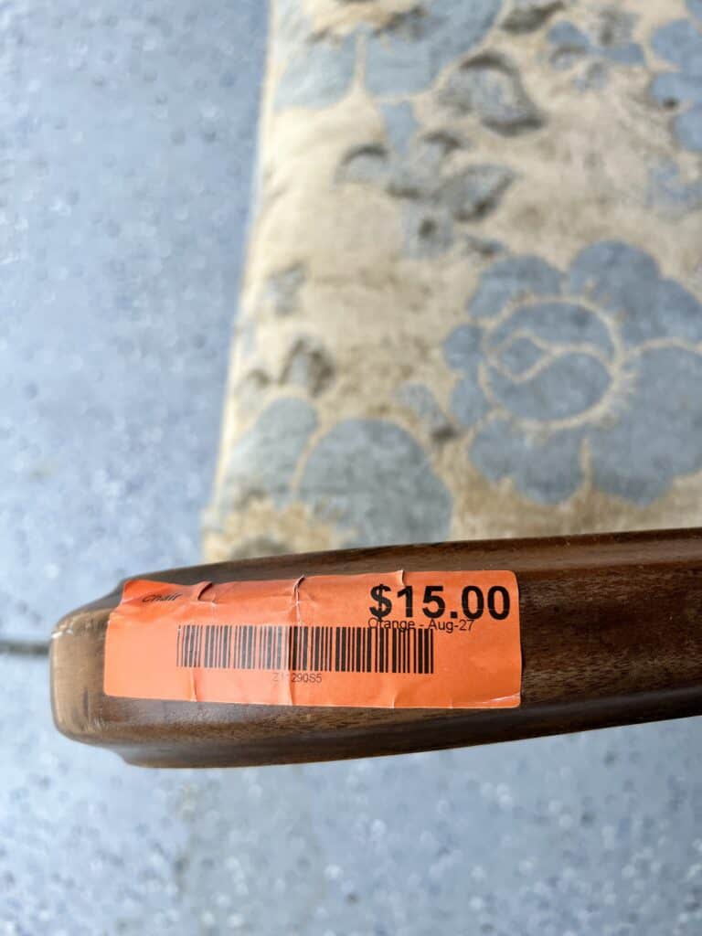 A $15 price tag ticker on the arm of a thrift store chair.