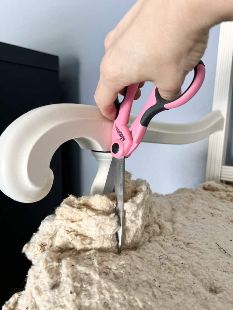 Trimming upholstery batting with scissors.