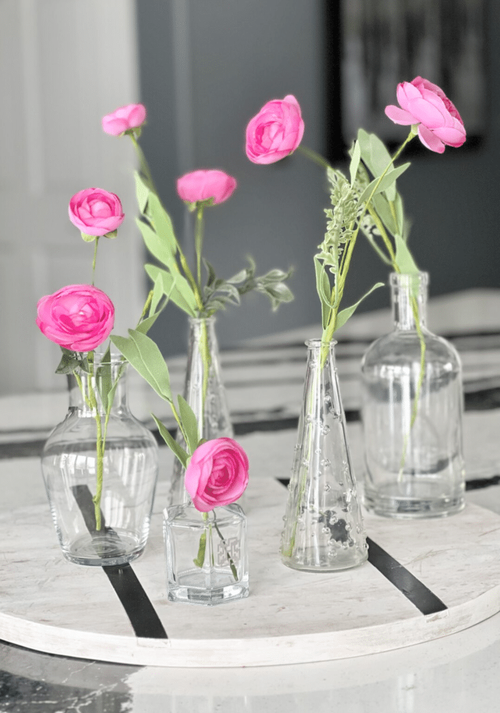 Single stems flowers in glass jars decorating a kitchen island countertop.