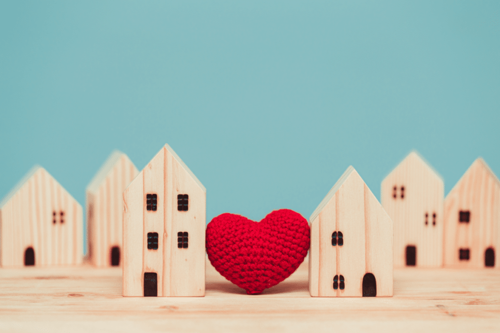 wooden houses sitting on a table with a crochet heart sitting in between.