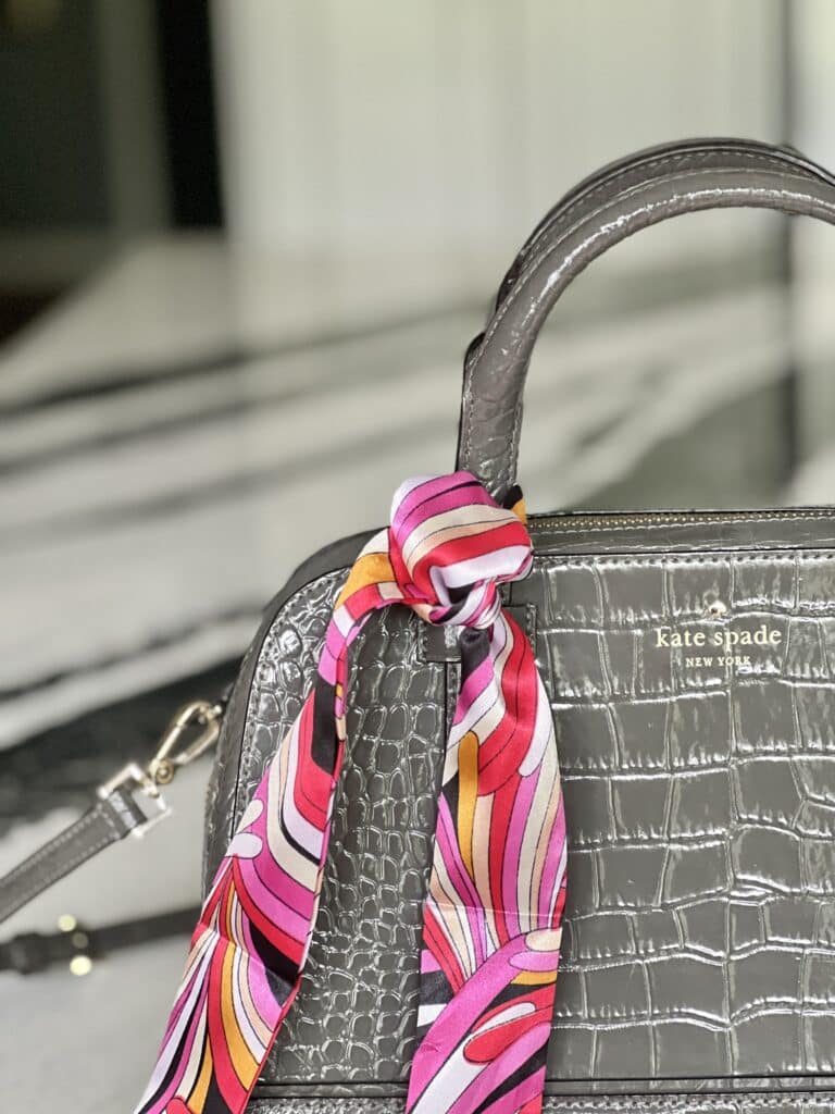 how to tie purse scarf: A skinny scarf tied in a simple knot on a purse.