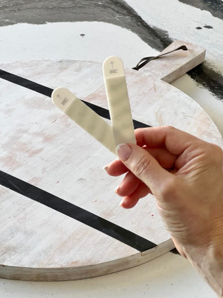 Adhesive strips used to hang cutting board on wall.