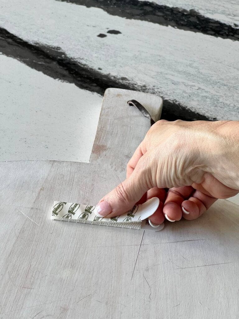 how to hang cutting board on wall: Pressing the second adhesive strips onto the first strip.