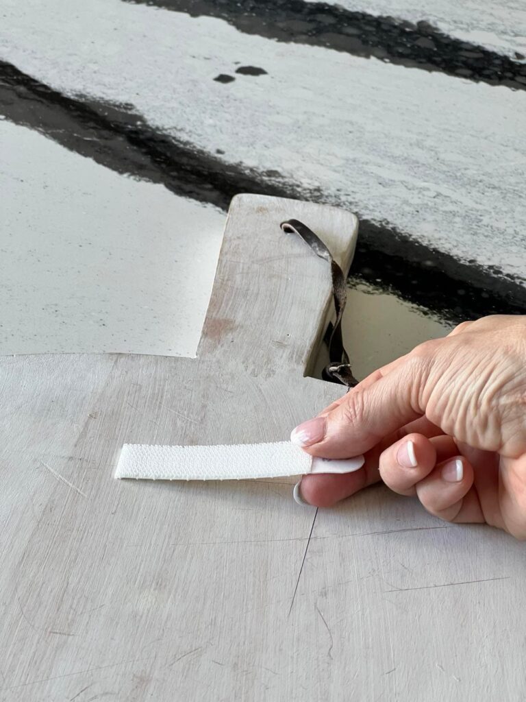 how to hang cutting board on wall: Pressing one adhesive trip to the back of the cutting board.