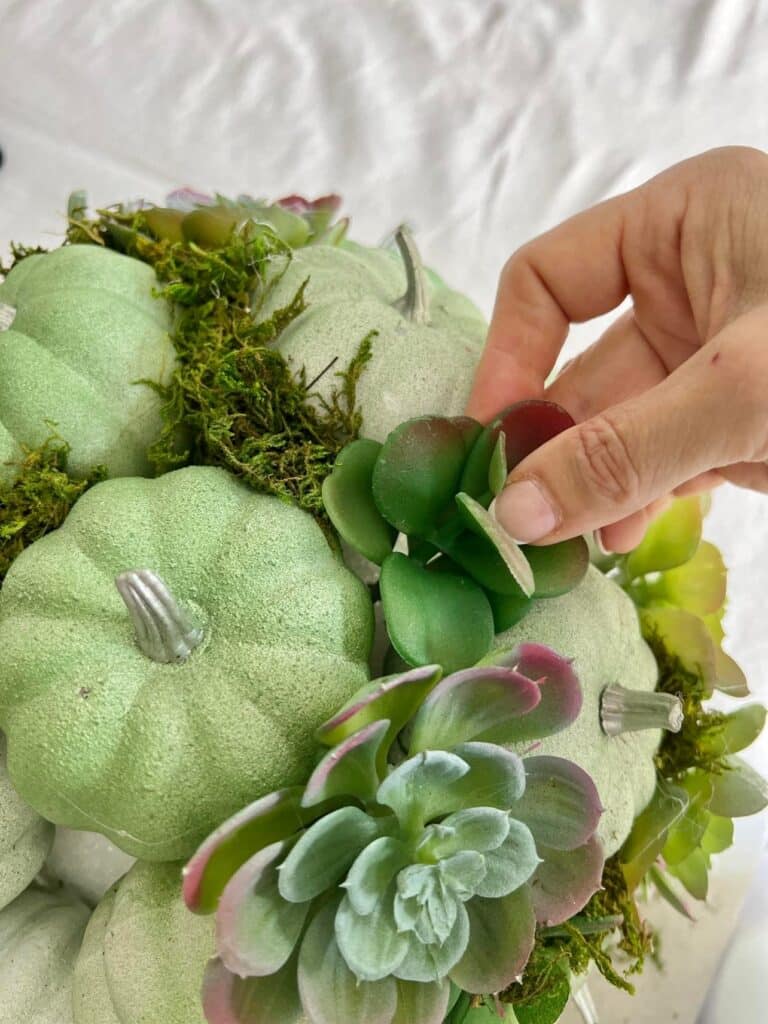 Adding a faux succulent to a pumpkin kissing ball project.