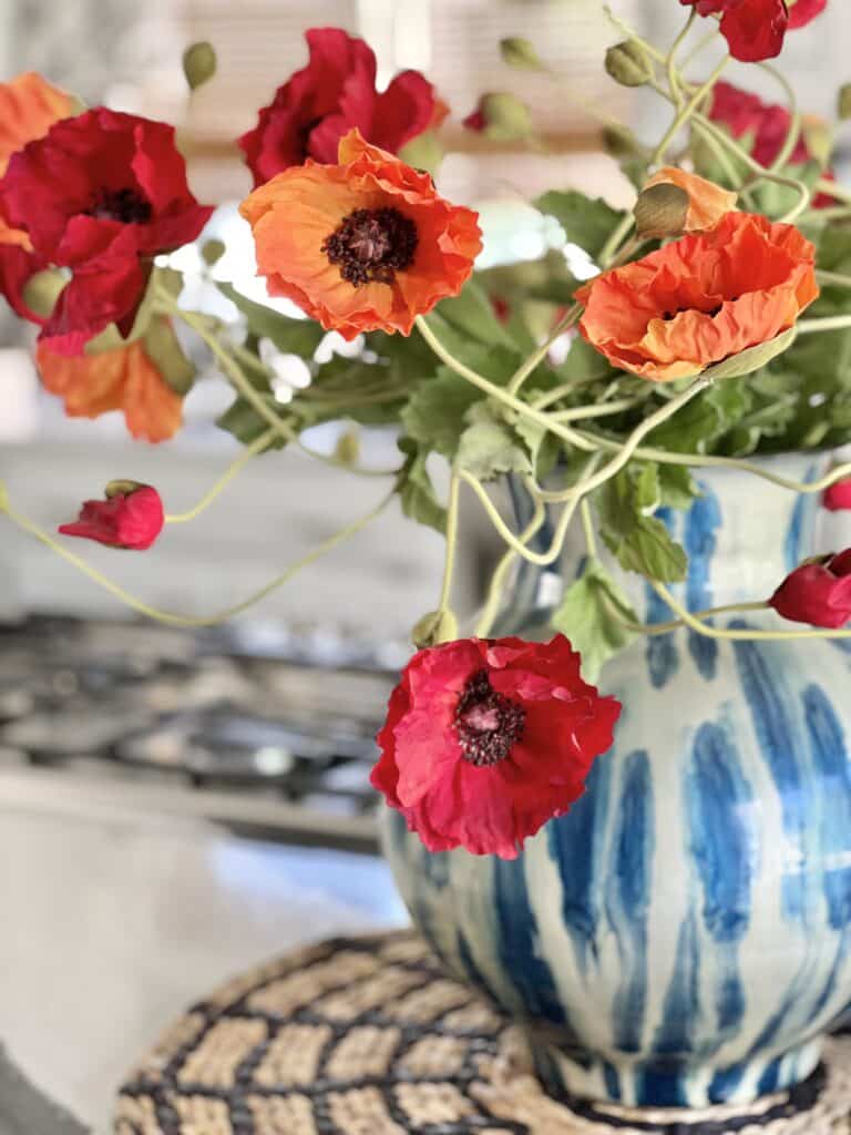 A simple table centerpiece consisting of a blue and white and red and orange faux poppies.