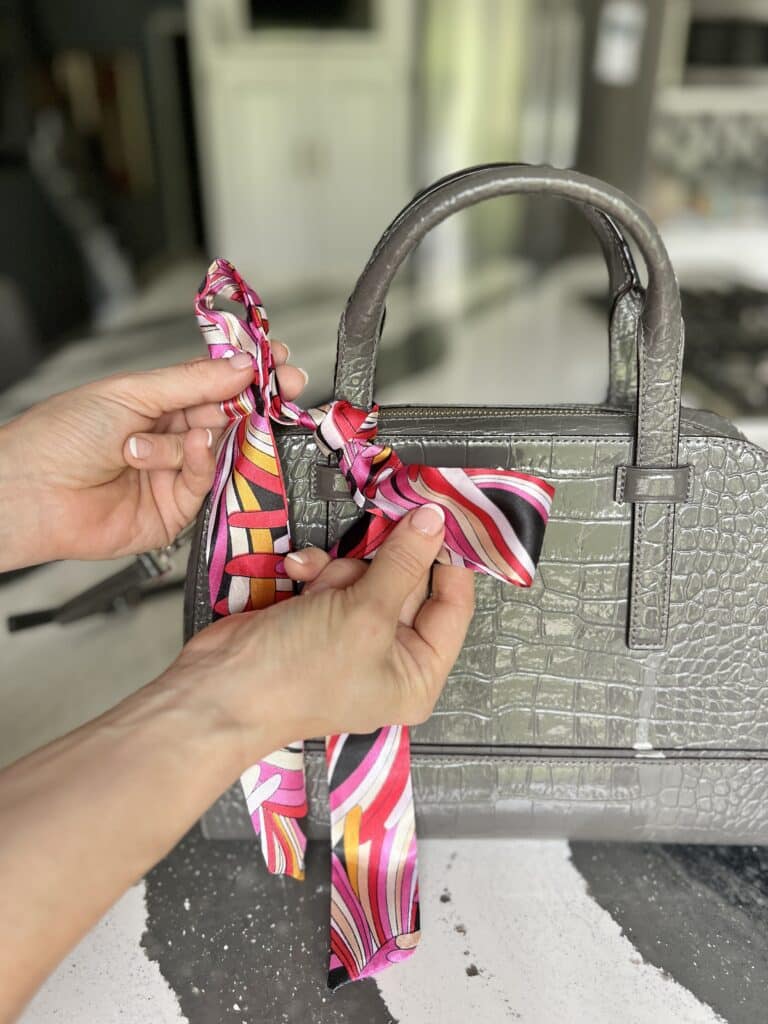 Close up of female leather handbag with tied scarf. Woman holds brown purse  with bouquet of white spring flowers. Stock Photo | Adobe Stock