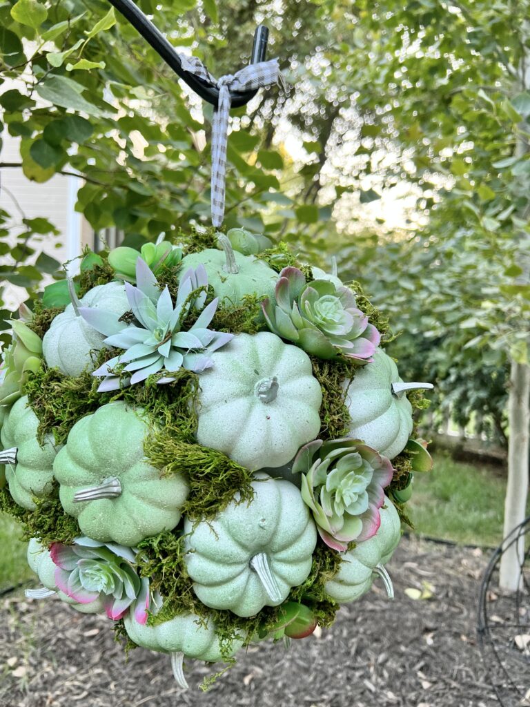 diy outdoor fall decor: a hanging pumpkin kissing ball in a backyard.