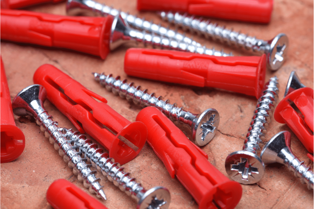 a pile of screws and red wall anchors.