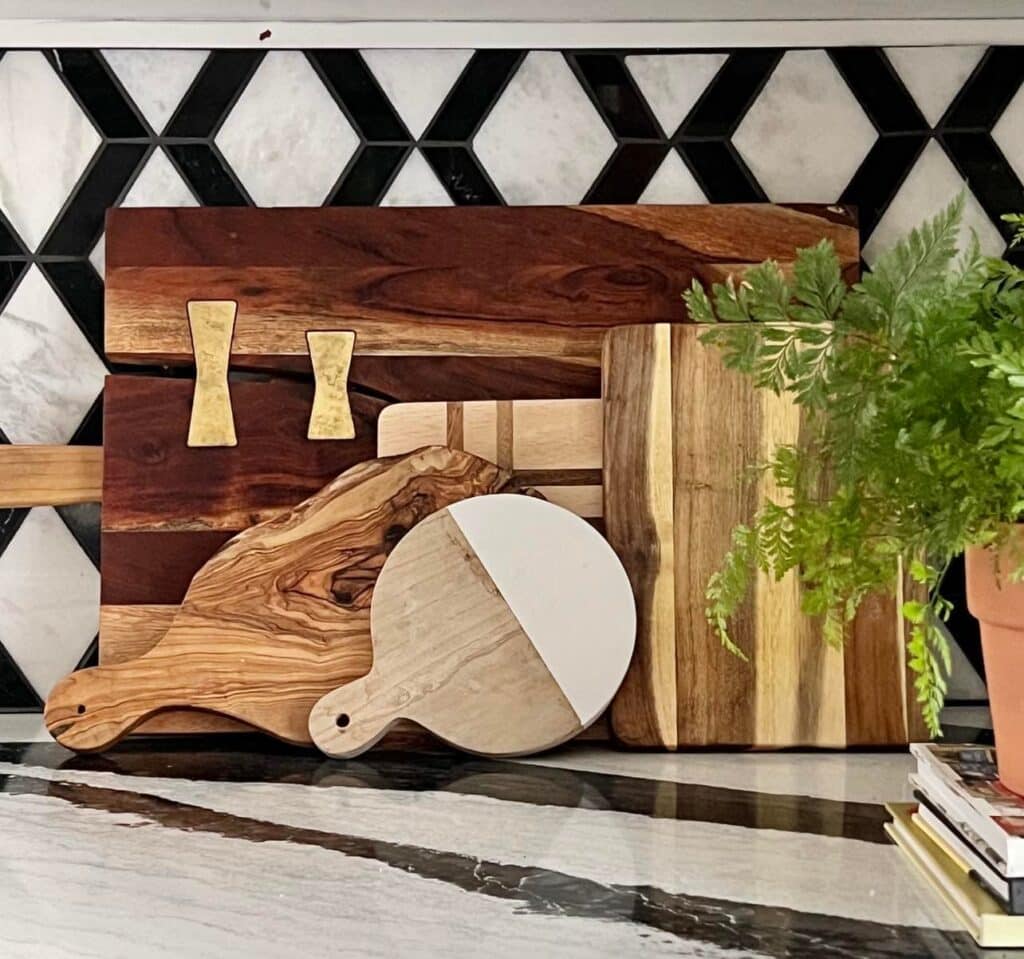 Wood cutting board layered against a kitchen tile backsplash.
