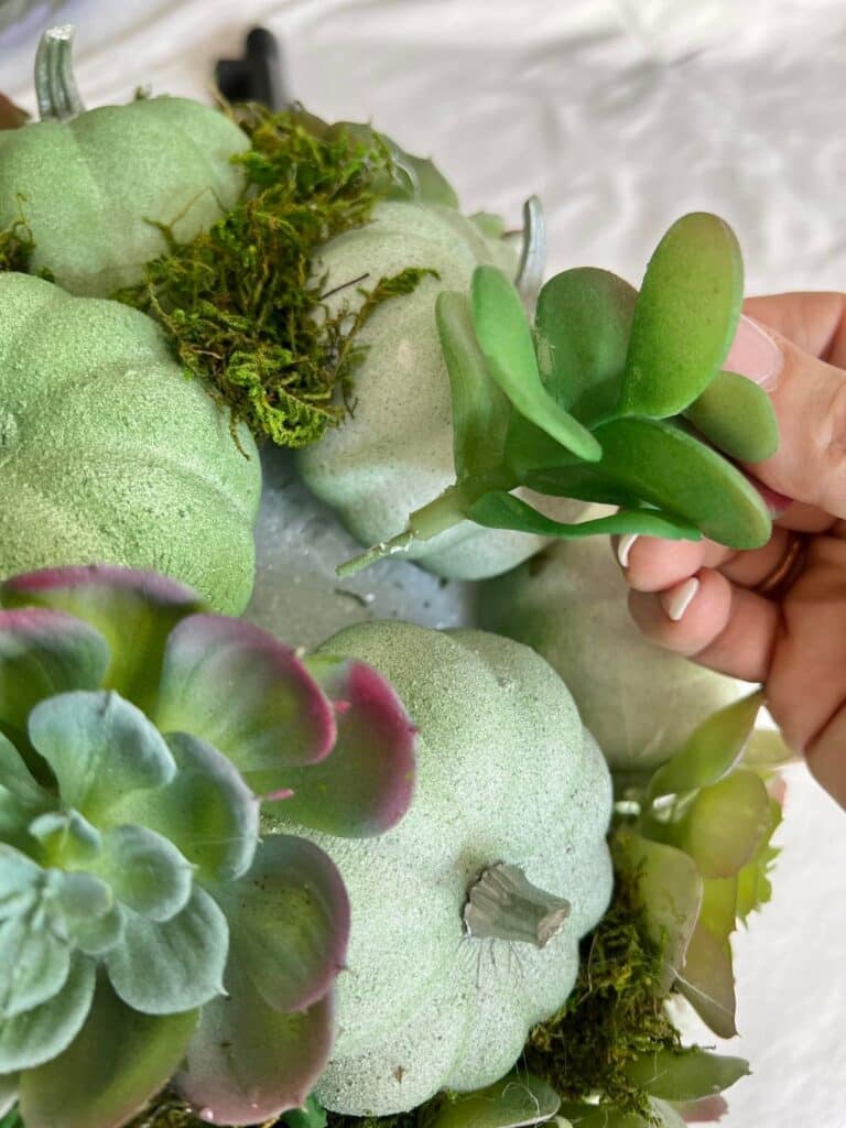 diy outdoor fall decor: sticking faux succulents into a styrofoam ball.