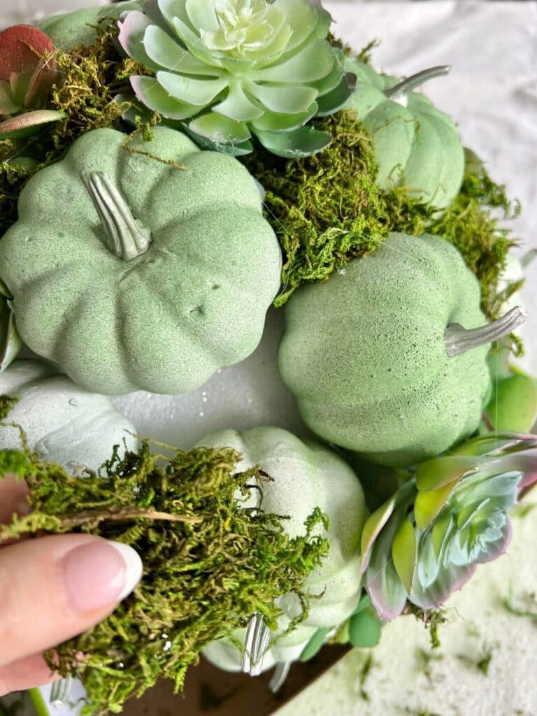 Adding green moss to the diy outdoor fall decor pumpkin kissing ball.