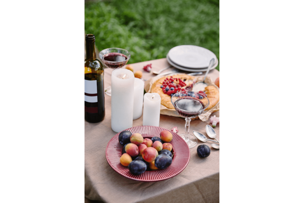 A boowl of fruit, three candles, and a bottle of wine.