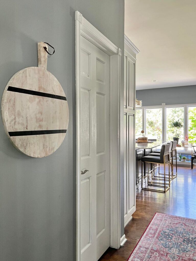 how to hang cutting board on wall: a round wooden cutting board hung on. awall using adhesive strips.