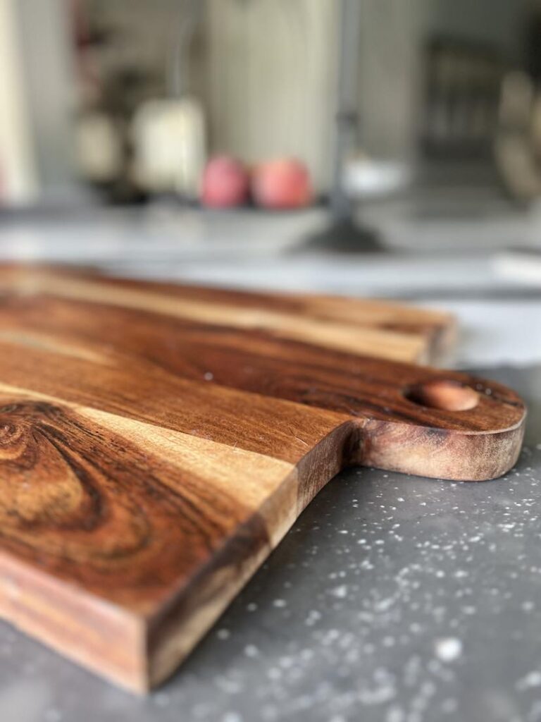 A wooden cutting board sitting on top of a kitchen island counter.