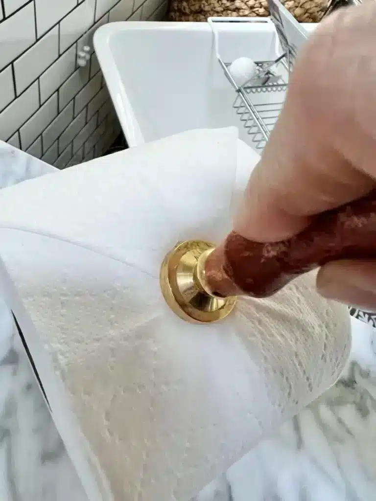 Pressing an embossing tool into the end of a roll of toilet paper.