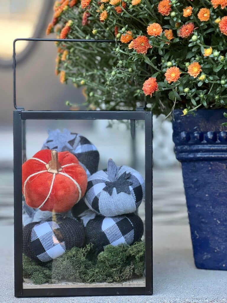 fall front porch decorating ideas on a budget: faux pumpkins inside a metal lantern.