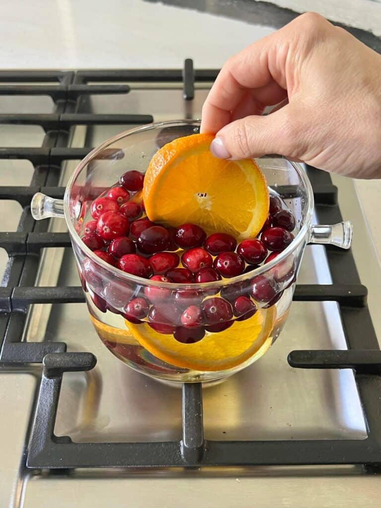 simmer pot recipes: Adding an orange slice to a pot.