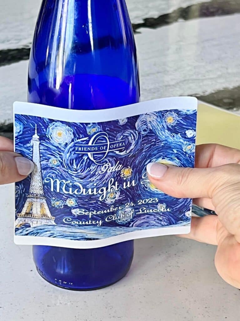 how to make wine  labels: applying a printed label to a blue wine bottle.