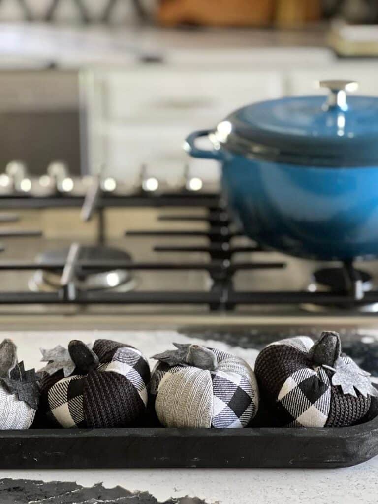 Black and white plaid fabric pumpkins nestled in a black dough bowl.