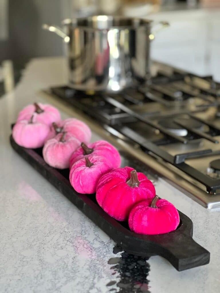 Bright pink faux pumpkins displayed on a kitchen island.