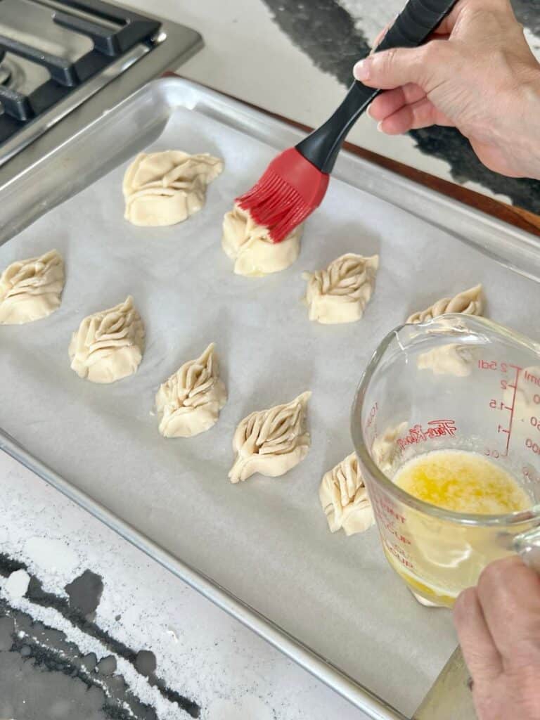 Brushing the leaf shaped cookies with melted butter before baking.