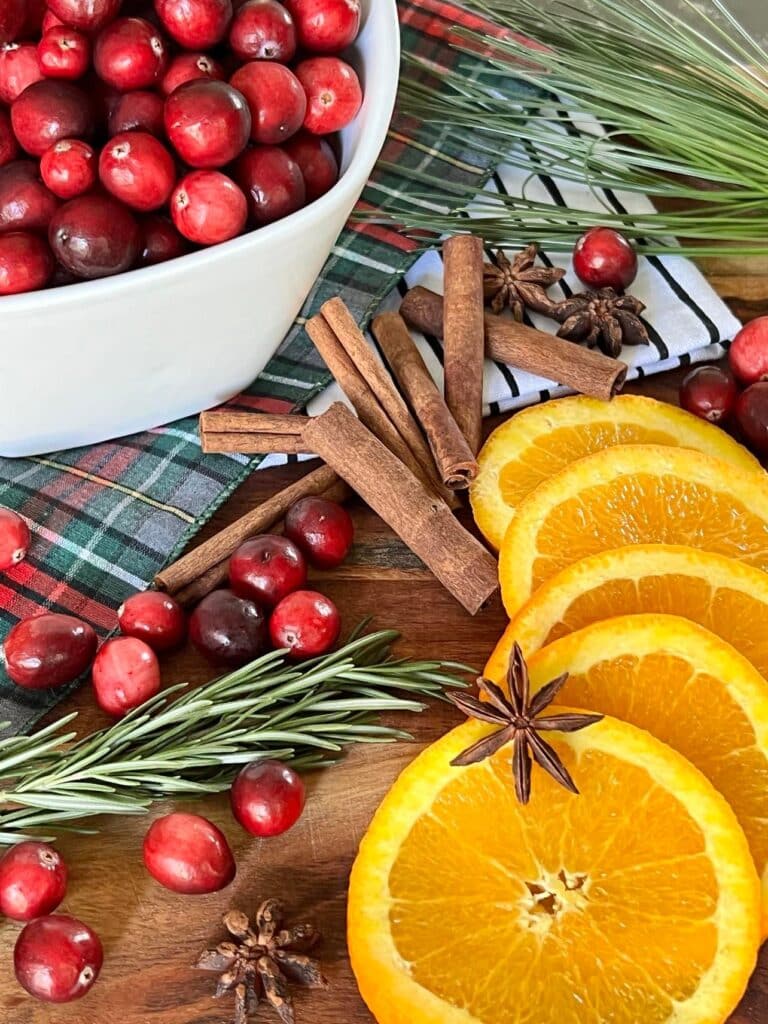 Ingredients for Christmas simmer pot recipes laying on a wood cutting board.