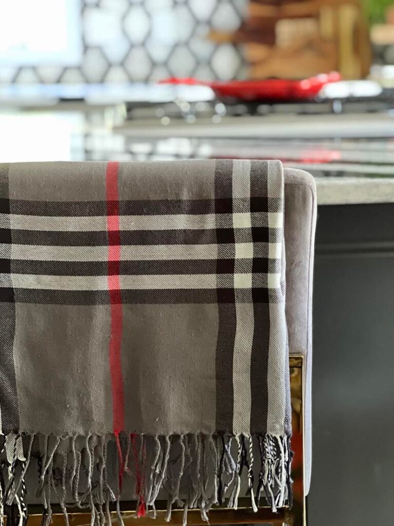 kitchen fall decor ideas: A bar stool seat draped with a grey, red, and black plaid scarf.