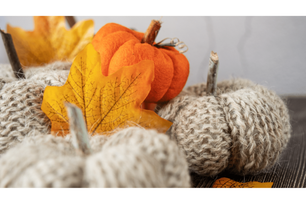 Orange and cream fabric wrapped pumpkins displayed with faux gold leaves.