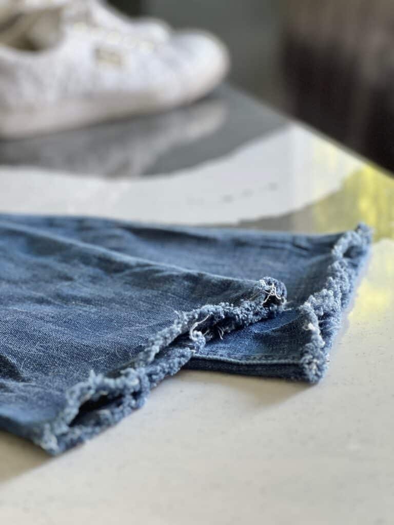 how to fray jeans: The hem of jeans that have been frayed and fluffed in the dryer.