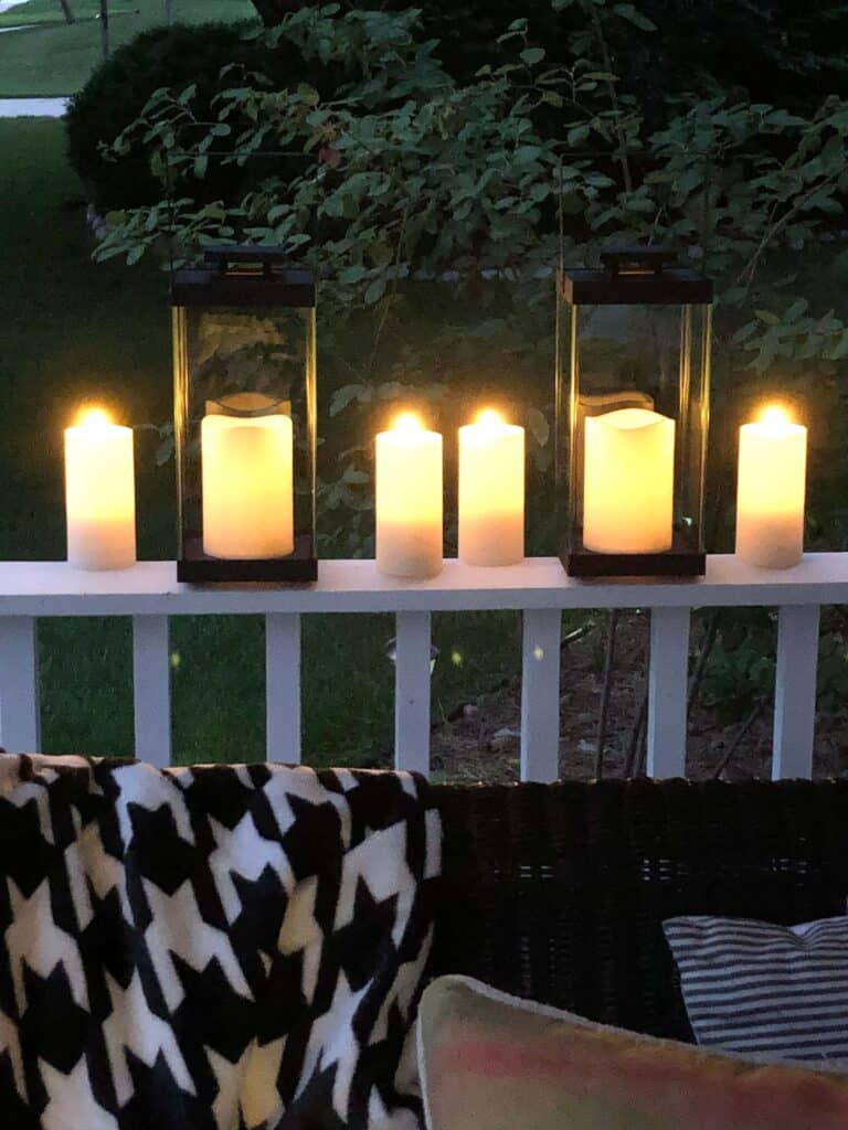 fall front porch decorating ideas on a budget: lanterns and LED candles illuminating a porch railing.