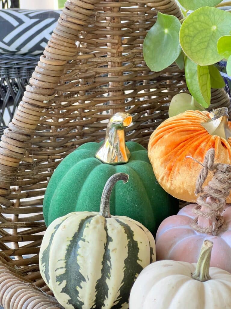Small faux pumpkins in a basket. fall front porch decorating ideas on a budget