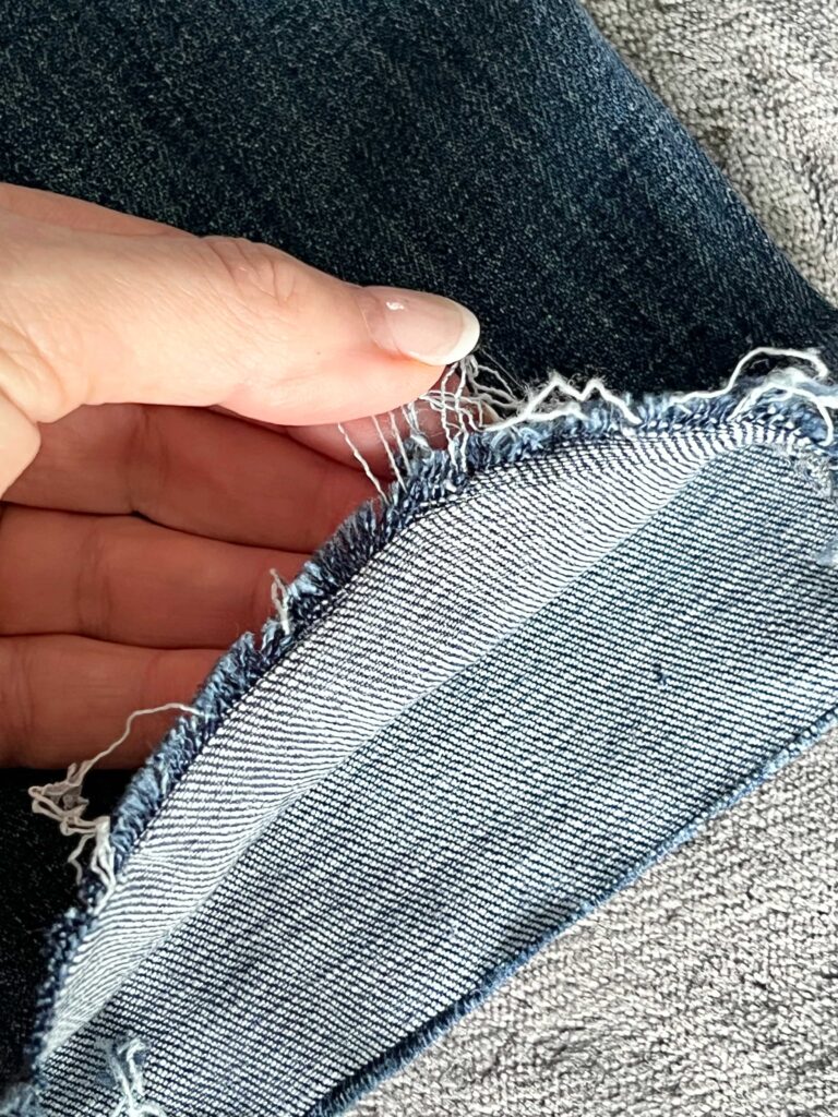 how to fray jeans: pulling threads from the hem with fingers.