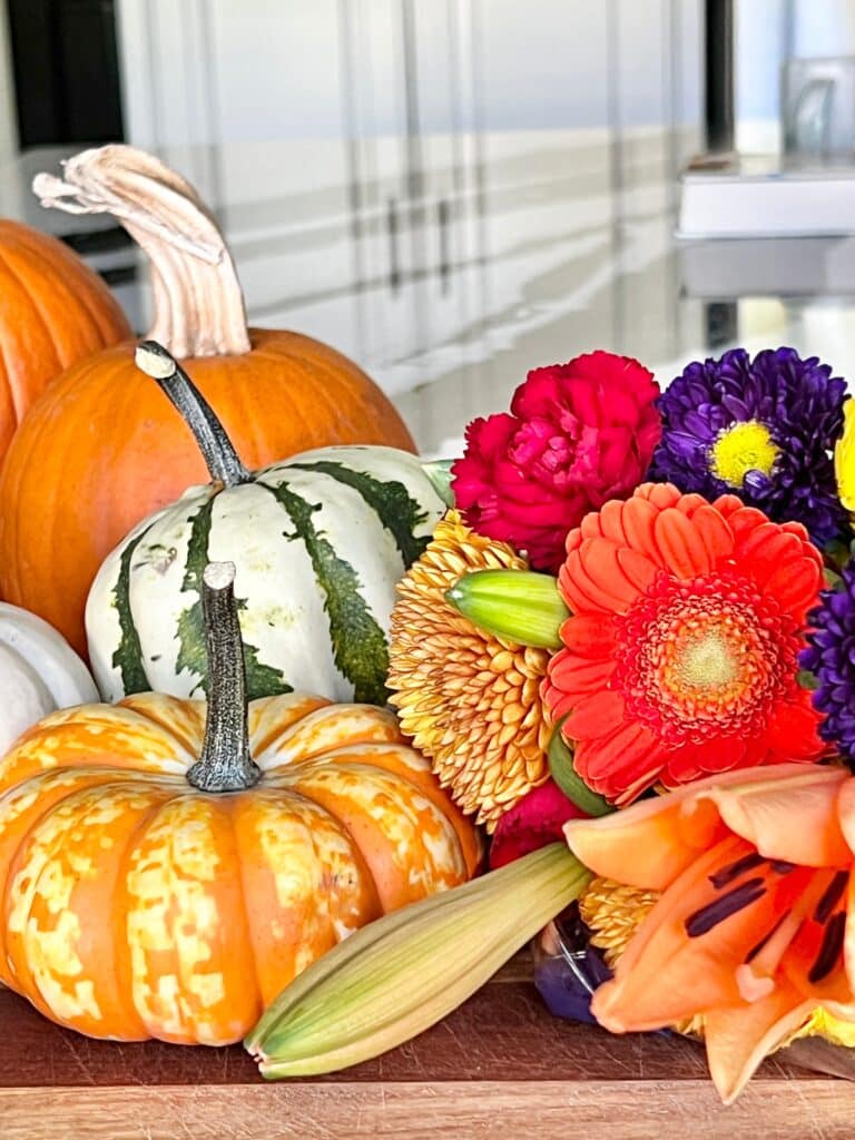 Pumpkins and colorful fresh flowers on aa kitchen counter.