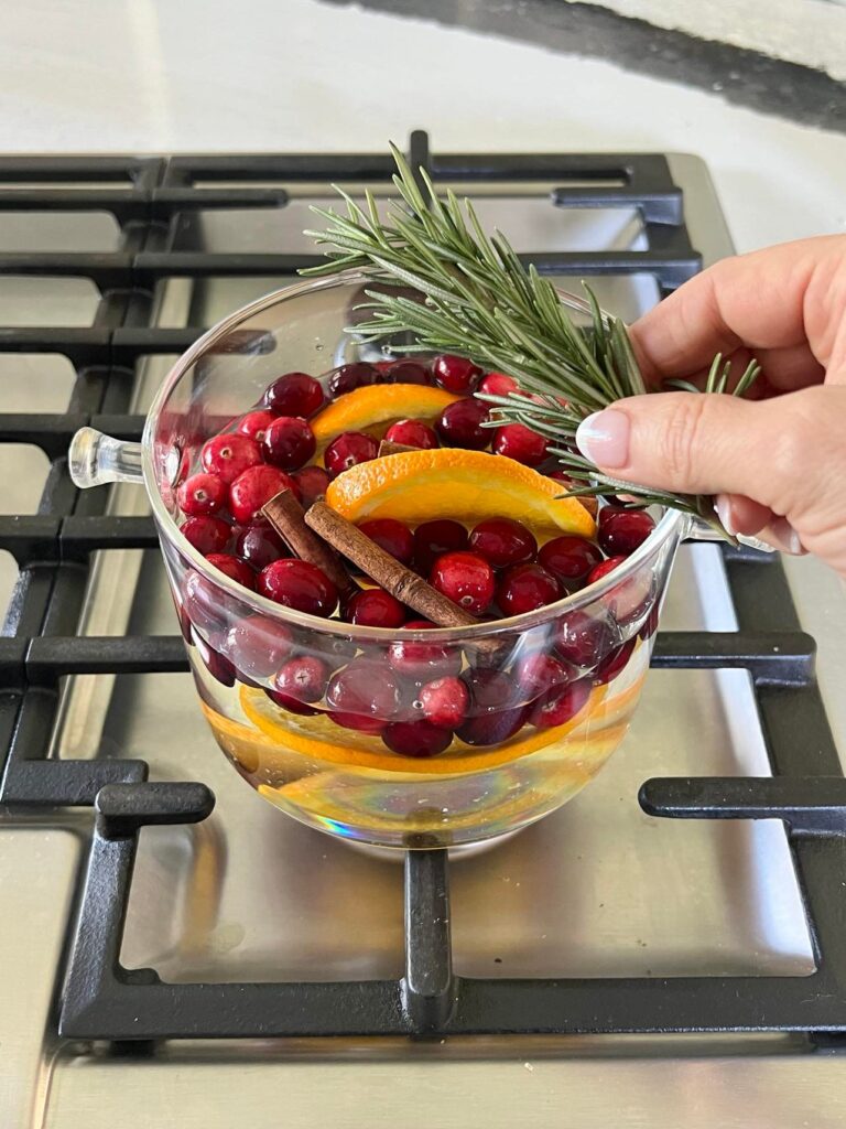 Dropping a sprig of rosemary into a saucepan.